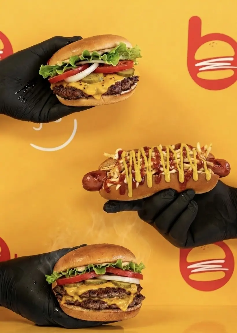 Burger Lab burgers and hot dog held up together
